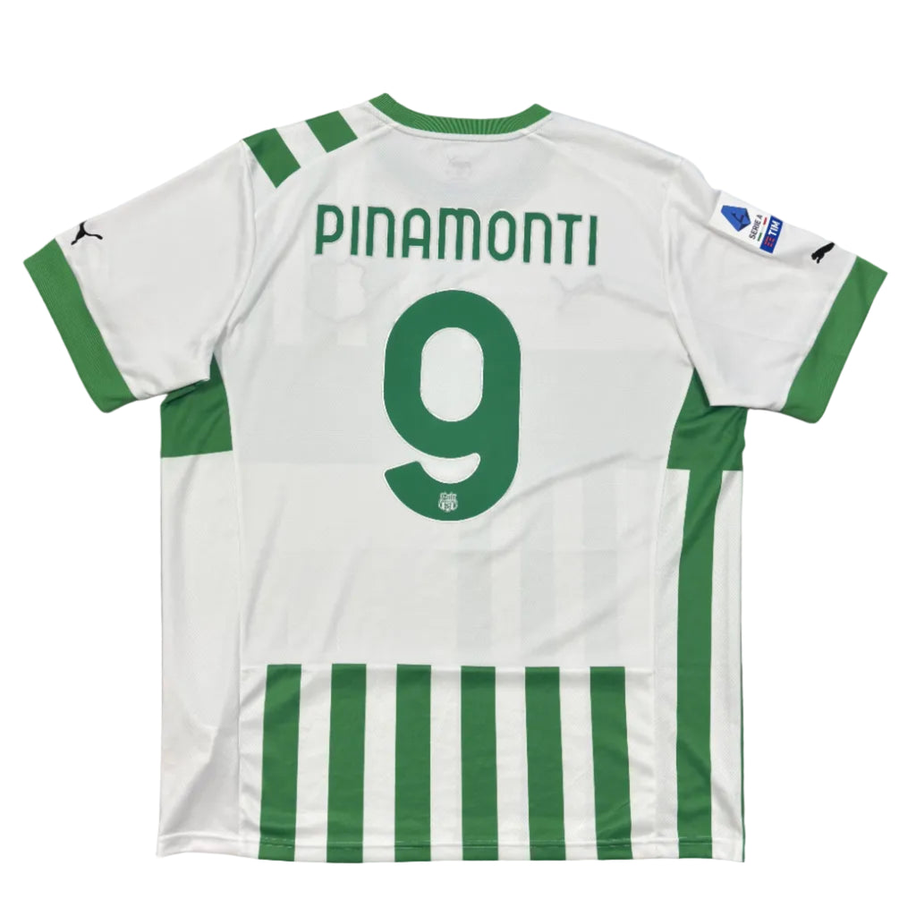 White sports jersey with green stripes and 'PINAMONTI' and number '9' on a gray surface.